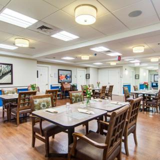 A spacious, well-lit dining area with wooden flooring and neatly arranged tables and chairs.