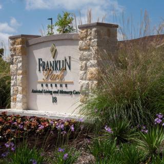 Entrance sign for Franklin Park surrounded by landscaped greenery and stone pillars.