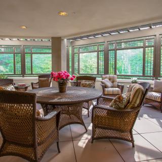 A cozy indoor patio featuring wicker furniture and large windows providing natural light.