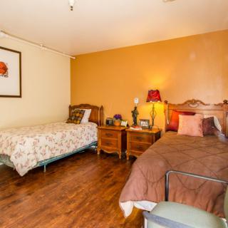 A cozy bedroom with two beds, wooden flooring, and a warm color scheme.