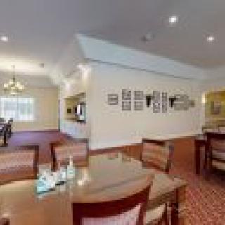 An elegant dining area with tables and chairs, featuring warm lighting and decorative wall accents.