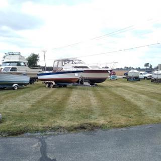 A collection of boats parked on grass at a marina.