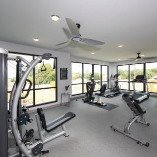 A well-equipped gym with exercise machines and large windows providing natural light.