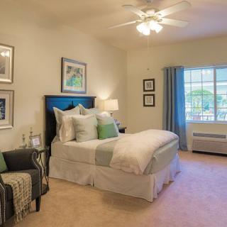 A well-decorated bedroom with a cozy bed, artwork on the walls, and a large window letting in natural light.