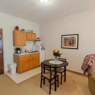 A cozy apartment interior featuring a small kitchen and dining area with a table and chairs.