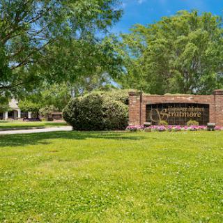 A welcoming entrance featuring a beautifully landscaped sign surrounded by lush greenery.
