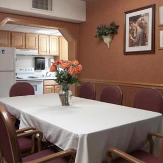 A cozy dining room with a white tablecloth and flower centerpiece near a kitchen.