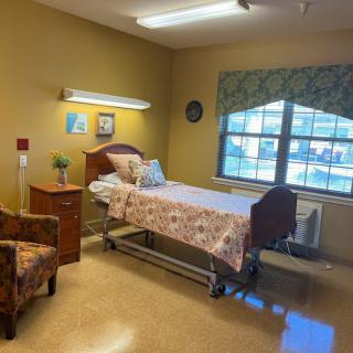 A well-lit hospital room with a single bed and comfortable furnishings.