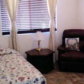 Cozy bedroom with a bed, armchair, and a lamp on a side table near the window.