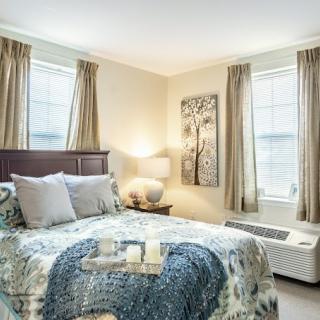 A cozy, well-decorated bedroom with a bed, artwork, and warm lighting.