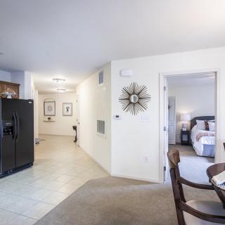 A modern apartment interior featuring an open layout with a view of both the kitchen and bedroom.