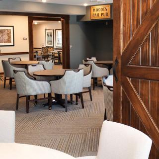A cozy dining area with neatly arranged tables and chairs, featuring a rustic wooden door.
