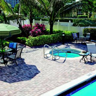 A serene outdoor patio area with a pool and hot tub, surrounded by lush greenery and comfortable seating.