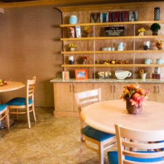 A cozy dining room with round tables and wooden shelves decorated with various items.