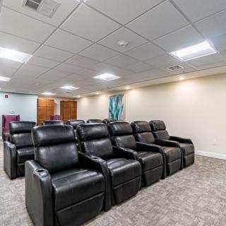 A modern home theater with leather recliner seating arranged in two rows.