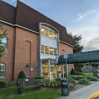 A modern brick building with large windows and a connecting walkway in an outdoor setting.