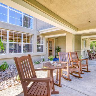 A cozy outdoor patio with wooden rocking chairs and tables, perfect for relaxation.
