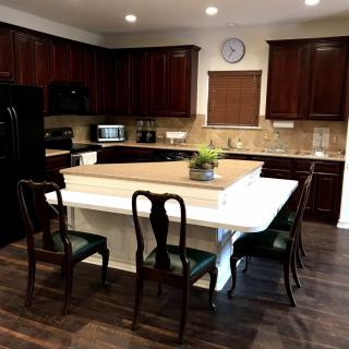 A modern kitchen with dark wood cabinets and a central island featuring dining chairs.
