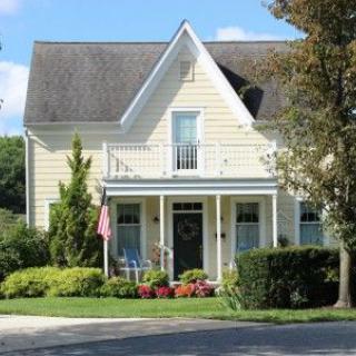 A charming two-story house with a porch and well-maintained garden.
