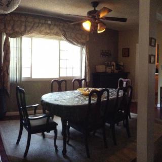 A cozy dining room with a table and chairs, illuminated by a ceiling fan light.