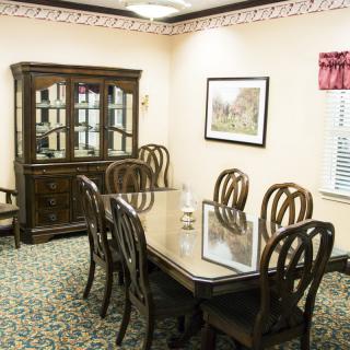 A dining room with a wooden table and chairs, along with a display cabinet and wall decor.