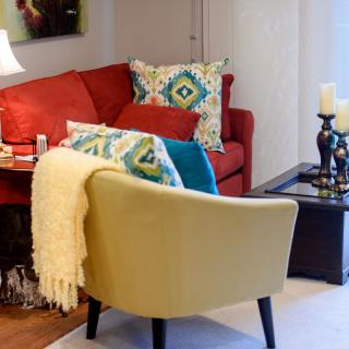 A cozy living room with a red sofa, accent pillows, and a comfortable armchair.
