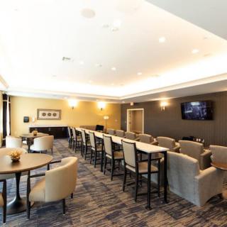 A modern conference room with rows of seating, tables, and a wall-mounted TV screen.