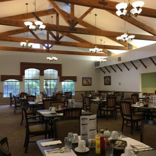 A spacious restaurant dining area with wooden beams and neatly arranged tables.