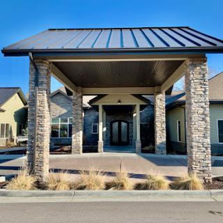 A modern entrance of a building featuring stone pillars and a metal roof.