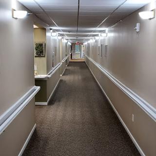 A long, well-lit hallway with carpeted floors and beige walls.