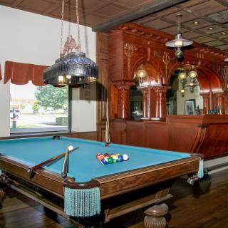 A stylish recreation room featuring a pool table and a classic bar setup with wooden paneling.