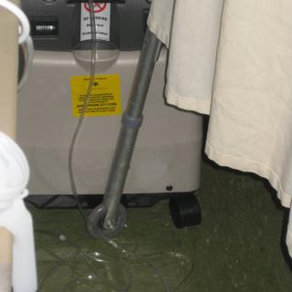 Medical oxygen concentrator next to a hospital bed with a curtain.