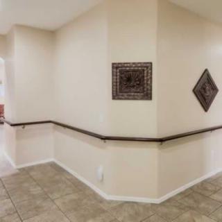 A hallway with tile flooring and decorative wall art.