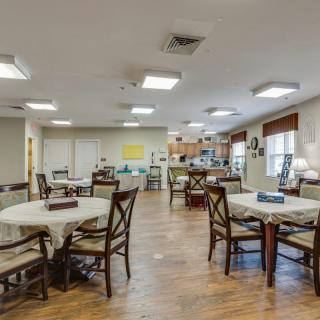 A spacious dining area with several tables and chairs arranged under bright ceiling lights.