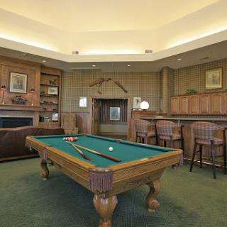 A cozy game room featuring a classic pool table, comfortable seating, and a warm fireplace.