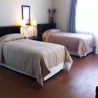 A tidy bedroom with two neatly made beds and a nightstand between them.