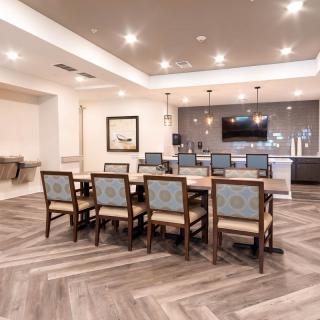 A modern conference room with a large table, chairs, and a television.