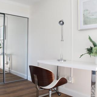 A minimalist home office with a sleek white desk and a modern chair, complemented by an indoor plant and wall art.