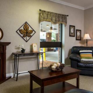 A cozy living room with a sofa, coffee table, and decorative elements like wall art and a lamp.
