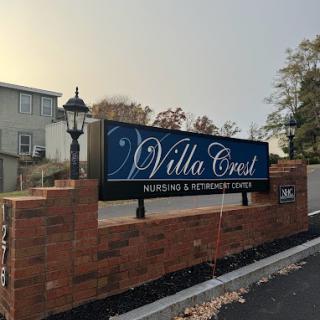 A sign for Villa Crest Nursing and Retirement Center displayed outside a brick structure.