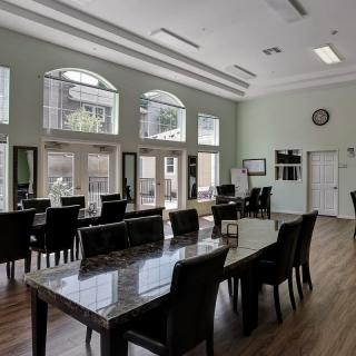 A modern dining room with large windows, wooden floors, and sleek furniture.