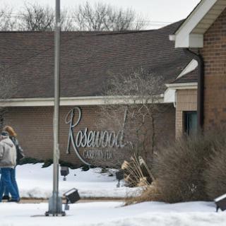 A snowy scene featuring a building with a prominent sign, as people walk by.