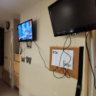 A view of a room featuring two mounted televisions and a bulletin board on the wall.