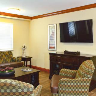 A cozy living room with patterned seating, a flat-screen TV, and wooden furniture.