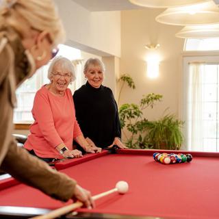 A group of seniors enjoy a friendly game of billiards indoors.