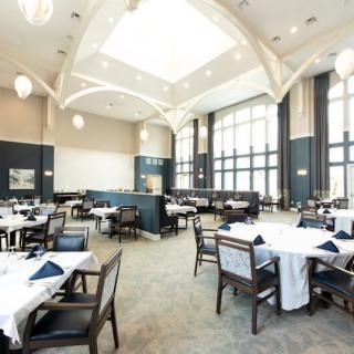 A spacious and elegantly designed restaurant interior featuring neatly arranged tables and chairs with ample natural light.