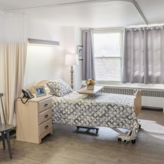 A comfortable and well-lit hospital room featuring a patient bed, bedside table, and a cozy atmosphere.