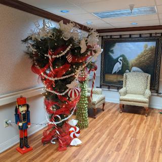 A festive holiday scene featuring a beautifully decorated Christmas tree and a nutcracker figure, set against an elegant backdrop with artwork.