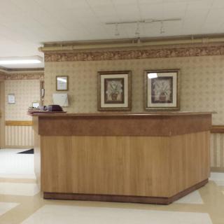 An empty reception desk in a lobby area with decorative wall art.