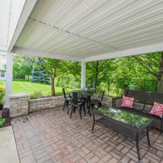 A covered patio with comfortable outdoor furniture overlooking a lush garden.